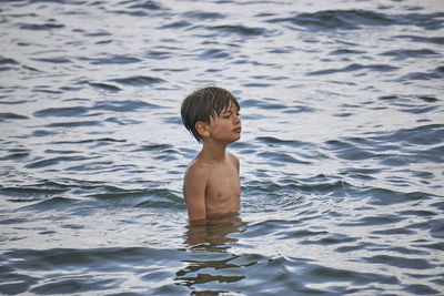 Shirtless boy standing in sea