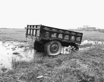 Abandoned truck on field against clear sky