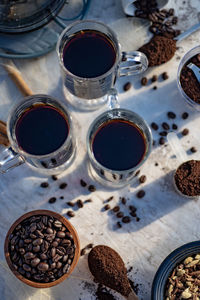 Still life with glass mugs of black hot coffee and coffee beans making coffee at home