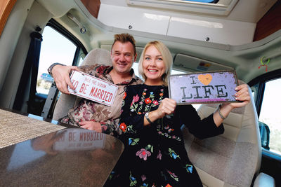 Portrait of smiling couple with message sitting in motor home