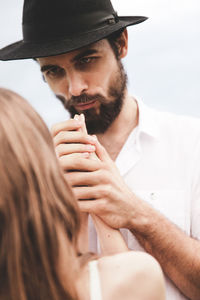 Boyfriend wearing hat looking at girlfriend against sky