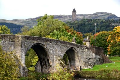 Arch bridge over mountains against sky