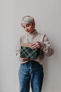 Portrait of young woman standing against wall