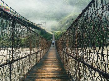 Rear view of person walking on wooden footbridge