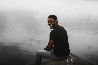 Portrait of happy man sitting by lake