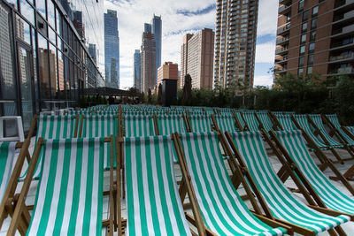 Green deck chairs amidst modern buildings in city