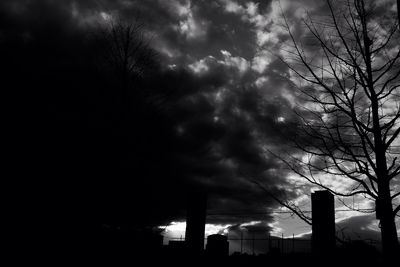 Low angle view of silhouette trees against cloudy sky