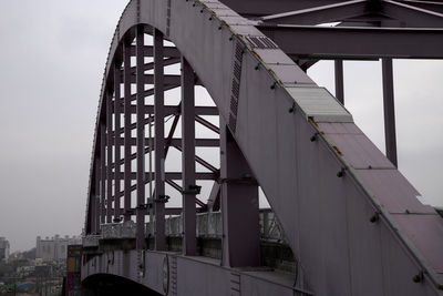 Low angle view of bridge and buildings against sky