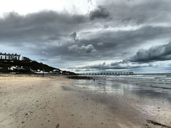 Scenic view of beach against cloudy sky