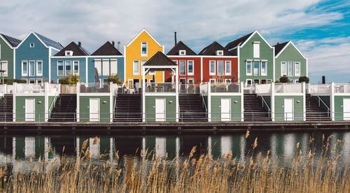 Houses by lake against sky