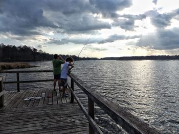 Rear view of people standing on railing against river