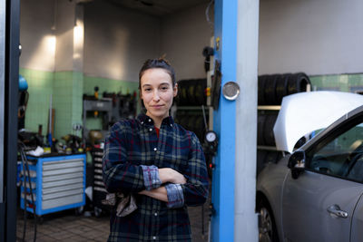 Female mechanic with arms crossed standing at workshop