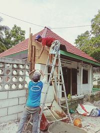 Rear view of man working against building