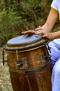 Midsection of woman playing drum outdoors