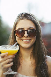 Portrait of young woman with cocktail wearing sunglasses