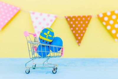 Close-up of easter eggs in shopping cart on table against bunting