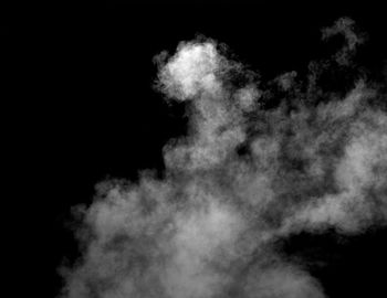 Low angle view of smoke against black background