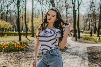 Portrait of beautiful young woman standing against plants