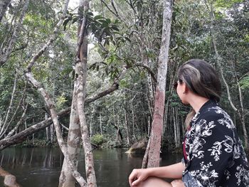 Midsection of woman by lake in forest