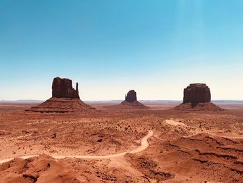 Rock formations on landscape against clear blue sky