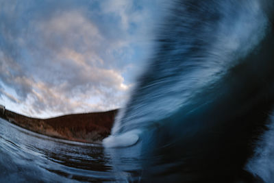 Slow motion wave breaking under sunset in front of a mountain