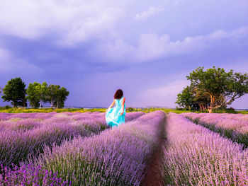 Rear view of woman on field against cloudy sky