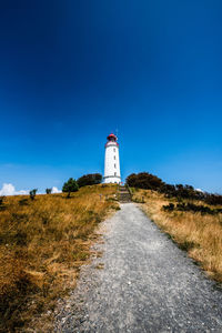 Lighthouse amidst plants and buildings against sky