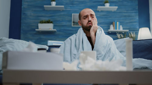 Ill man sitting on sofa at home