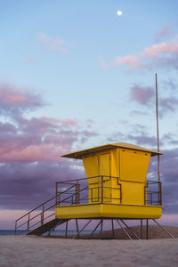 Lifeguard hut by sea against sky during sunset
