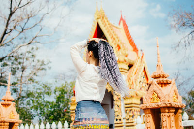 Rear view of man standing outside temple against building