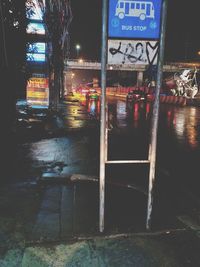 Illuminated road sign on street in city at night