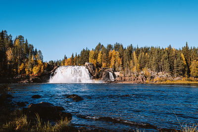 Scenic view of waterfall against clear blue sky