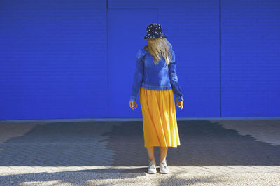 Rear view of woman standing against blue wall