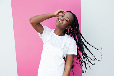 Portrait of young woman with arms crossed standing against white background