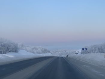 Road amidst snow covered trees against sky