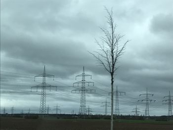 Low angle view of electricity pylon on field against sky