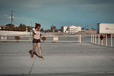 Full length of woman on street against sky in city