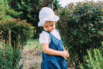 Little girl walks in the garden among beautiful evergreen southern plants