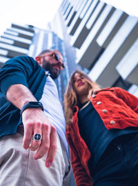 Low angle view of couple standing against building in city