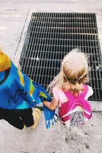 Mother and daughter holding hands while standing by manhole