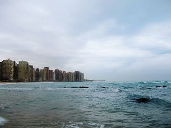 Sea by buildings against sky in city