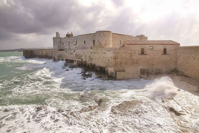 Building by sea against sky