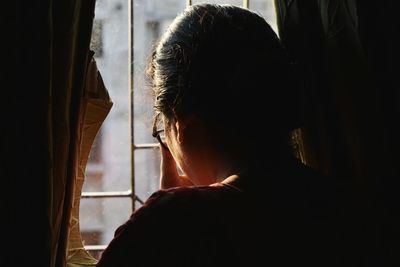 Close-up of man looking through window at home