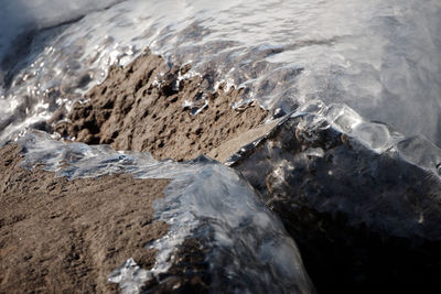 High angle view of snow covered rocks in sea