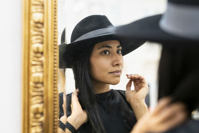 Young woman in black hat looking in mirror