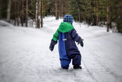 Rear view of boy walking in snow