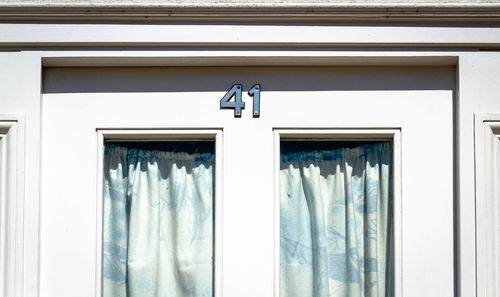 House number 41 on a white wooden front door in london with curtains 