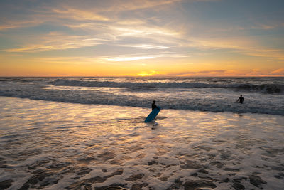 Silhouette man walking at beach against sky during sunset