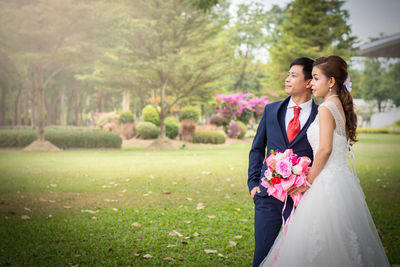 Bride and bridegroom standing at park