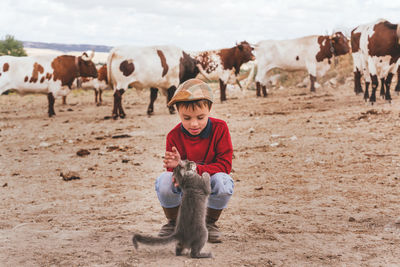 Cute smiling boy playing with cat outdoors